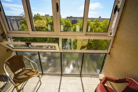 Glazed balcony with chairs and a view of greenery and the city. - image 6