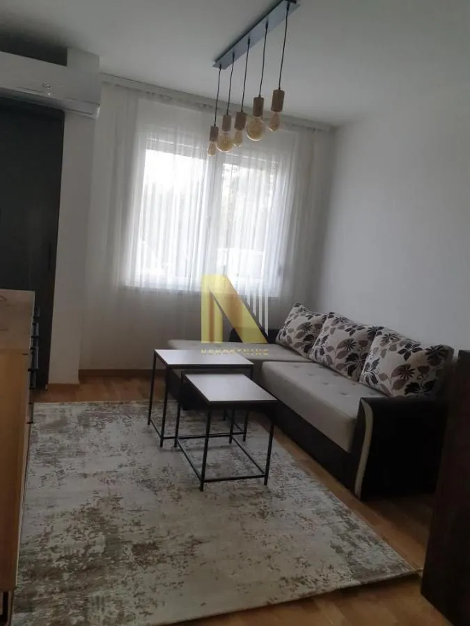 Dnevna soba sa ugaonom garniturom, stočićima i tepihom pored prozora.