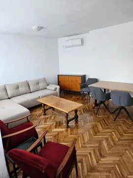Spacious living room with a sofa, wooden table, and parquet flooring. - image 2