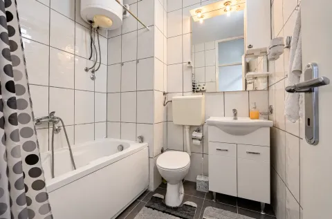 Small bathroom with a bathtub, washbasin, and toilet. - image 8