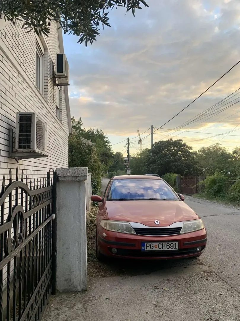 Exterior of a house with a parked car in front of the fence.