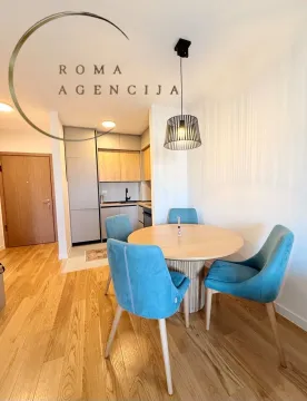 Dining area with a table and turquoise chairs, with a view of the kitchen. - image 2