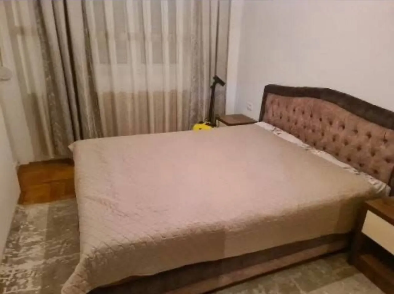 Namještena spavaća soba sa bračnim krevetom i noćnim stočićima.
