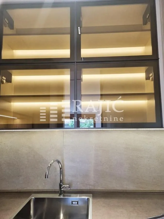 Modern kitchen upper cabinets with lighting and a sink.