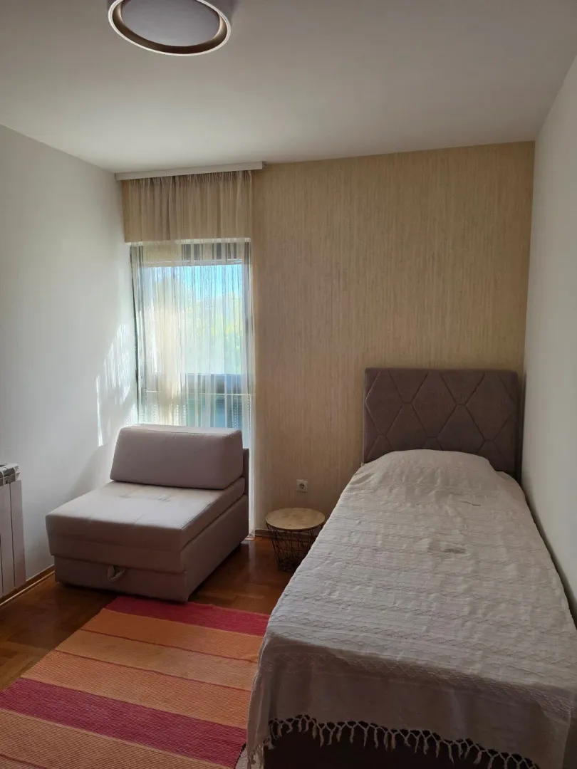 Furnished bedroom with a bed, armchair, and window.