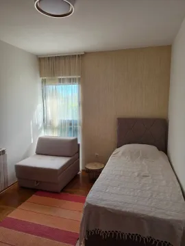 Furnished bedroom with a bed, armchair, and window. - image 4