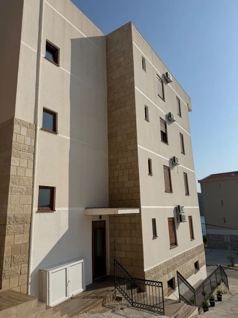 Spoljašnji izgled moderne stambene zgrade sa stepeništem i ulazom.