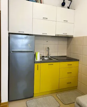 Manja kuhinja sa žutim donjim i bijelim gornjim elementima i frižiderom. - image 3