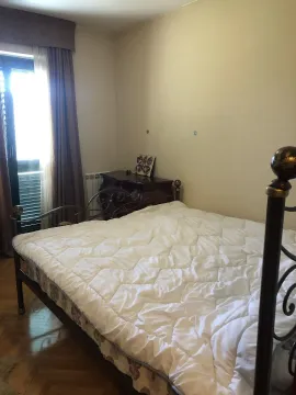 A bedroom with a metal frame bed and a wooden dresser near the balcony door. - image 20