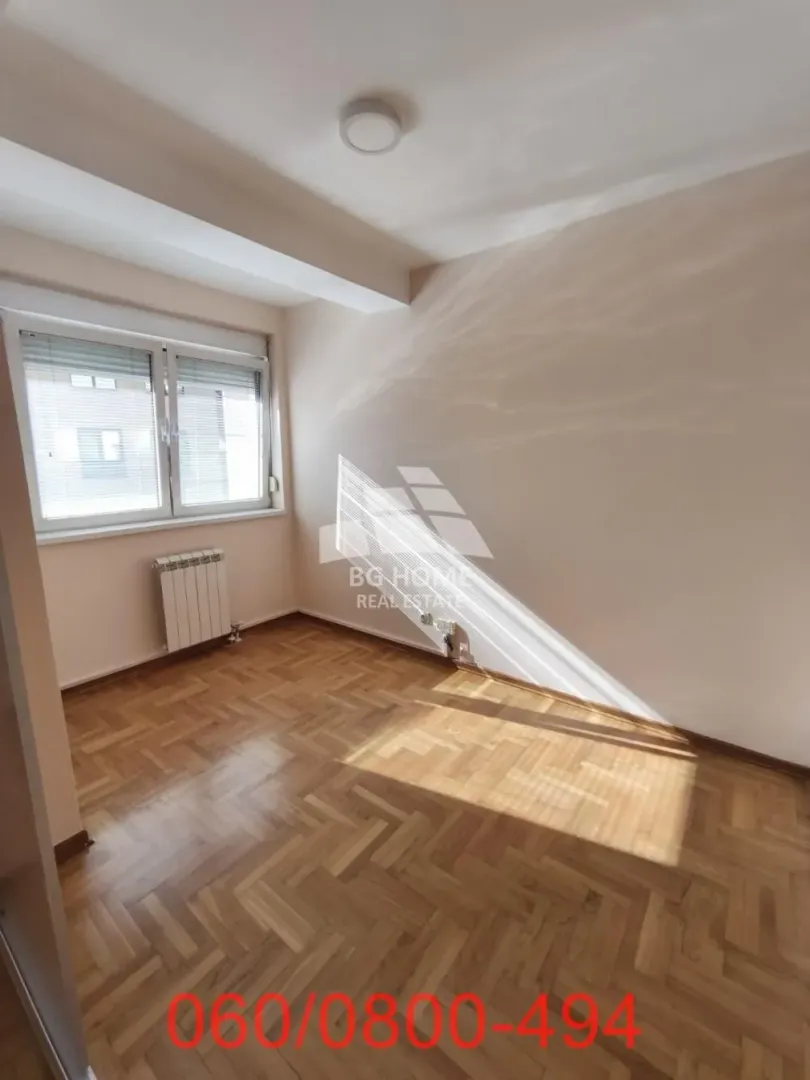 Empty room with parquet flooring and a window.