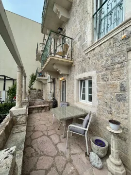 Stone building facade with balconies and a table with chairs in the yard. - image 11