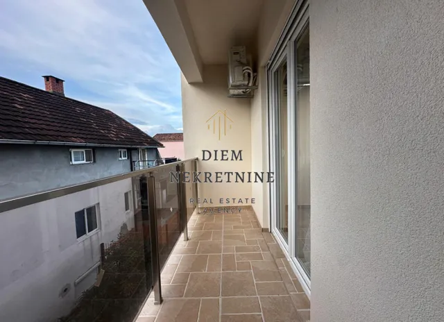 Empty covered balcony with tiled flooring and glass railing.