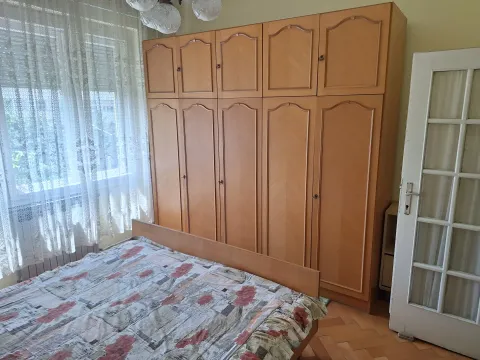 Spavaća soba sa drvenim garderoberom, krevetom i prozorom sa zavesama. - image 3