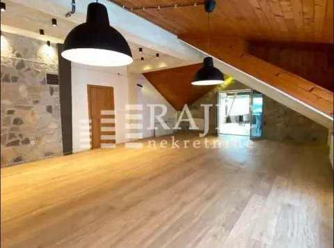 Spacious attic room with wooden flooring, wooden ceiling, and modern lighting fixtures. - image 12
