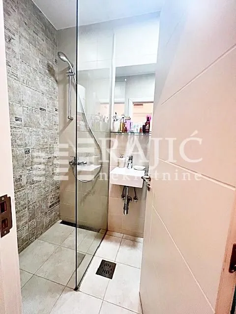 Small bathroom with a walk-in shower and a washbasin.