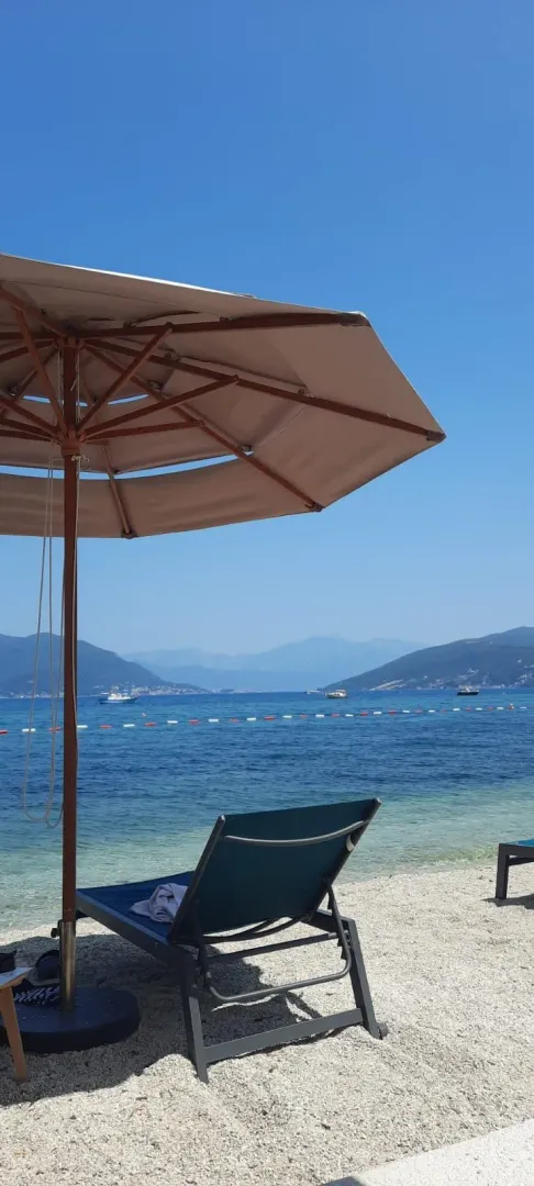 Pogled na more sa suncobranom i ležaljkom na plaži.