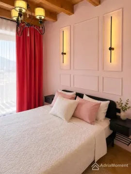Uređena spavaća soba sa bračnim krevetom, roze zidovima i drvenom plafonskom konstrukcijom. - image 8
