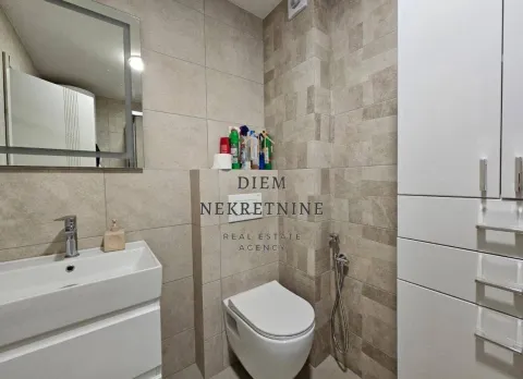 Modern equipped bathroom with a washbasin, toilet, and tiled walls. - image 6