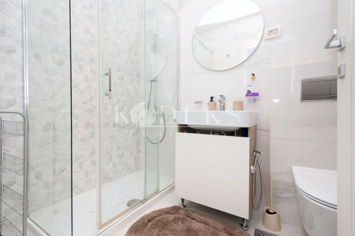 Savremeno opremljeno kupatilo sa tuš kabinom, umivaonikom i WC šoljom.