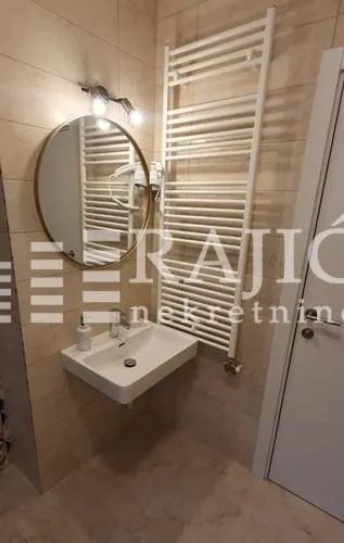 Modernly equipped bathroom with a washbasin, mirror, and towel radiator.