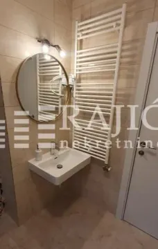 Modernly equipped bathroom with a washbasin, mirror, and towel radiator. - image 11