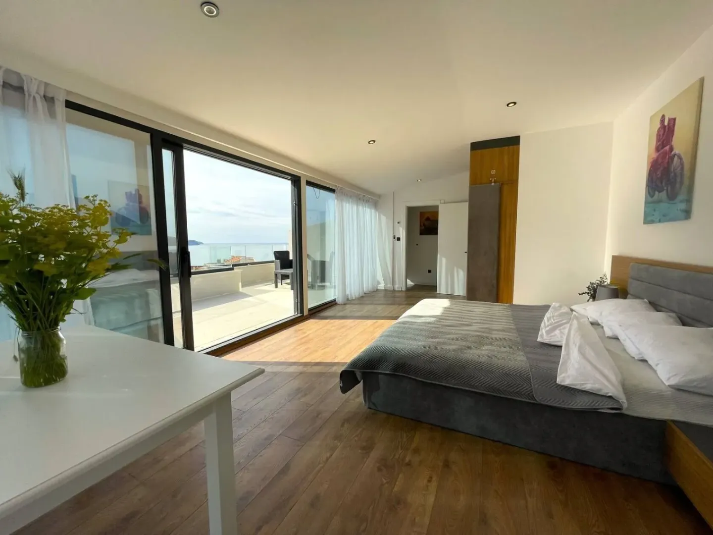 Spacious bedroom with large glass surfaces and access to a terrace with sea view.