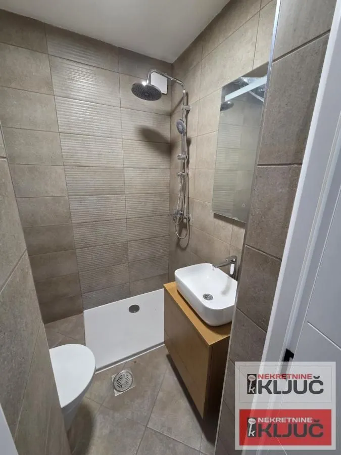 Manje kupatilo sa tuš kabinom, umivaonikom i wc šoljom.