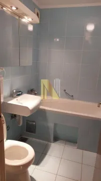Small light blue tiled bathroom with a bathtub, washbasin, and toilet. - image 11