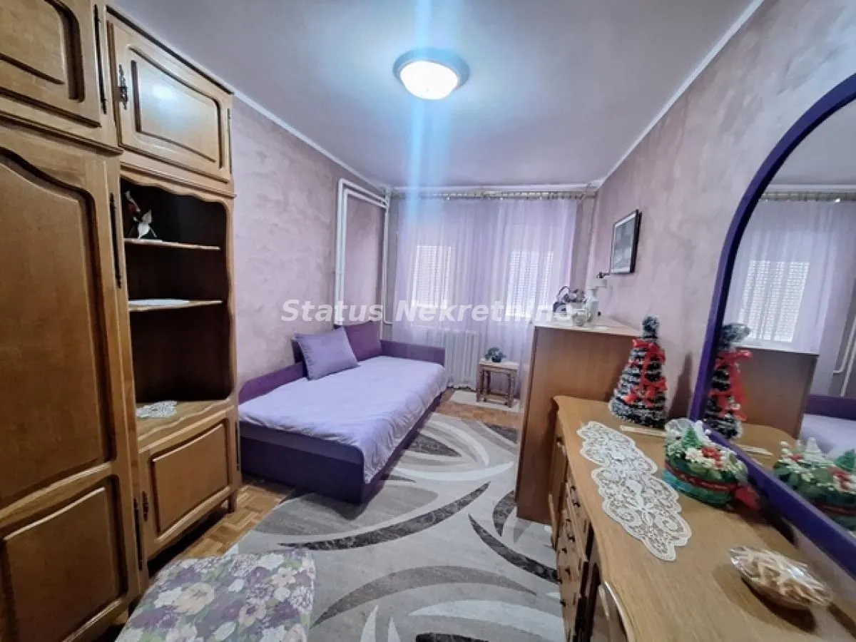 Nameštena spavaća soba sa krevetom i drvenim ormarima.