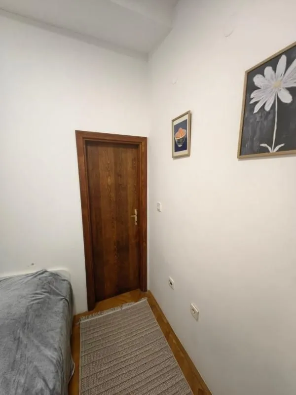 Manja spavaća soba sa drvenim vratima i slikama na zidu.