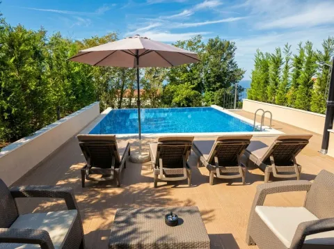 Terrace with swimming pool and sun loungers surrounded by greenery. - image 10