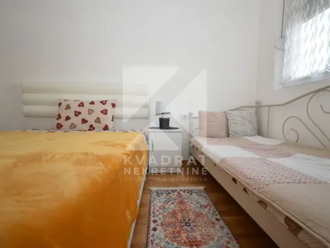Spavaća soba sa dva kreveta, noćnim stočićem i tepihom. - image 8