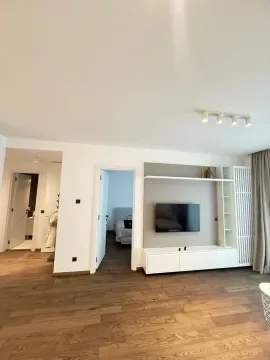 Living room with a TV unit and a view of the hallway and bedroom. - image 2
