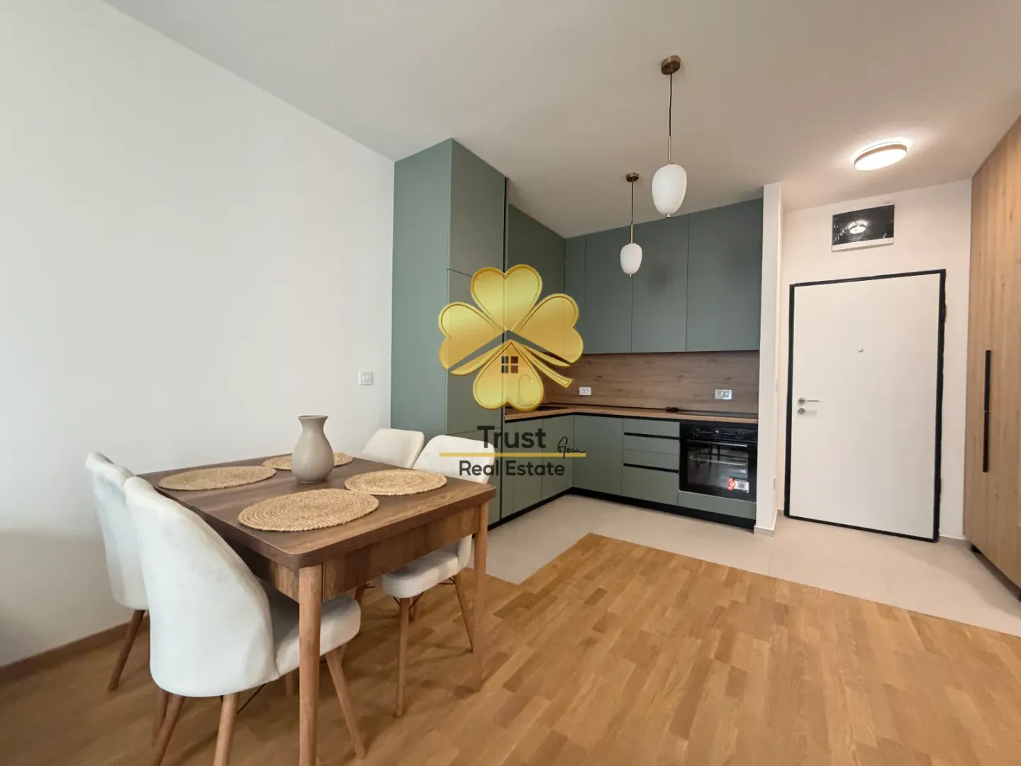 Modern kitchen with dining area and green cabinets.