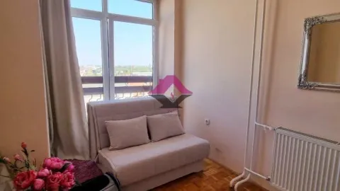 Manja dnevna soba sa kaučem i prozorom koji gleda na okolinu. - image 9