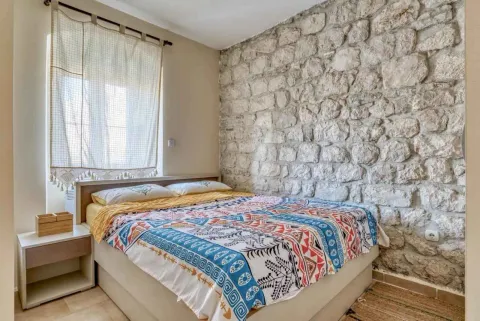 Spavaća soba sa bračnim krevetom i zidom od kamena. - image 11