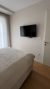 Uređena spavaća soba sa bračnim krevetom i zidnim televizorom. - image 8