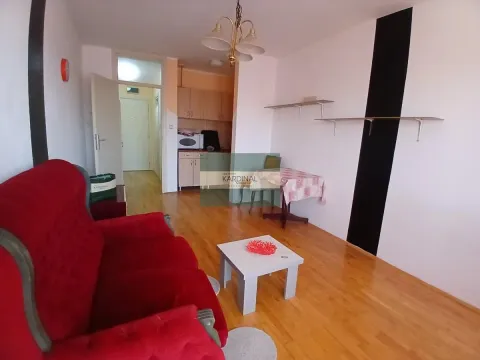 Living room with a red armchair, small coffee table and a kitchen in the background. - image 11