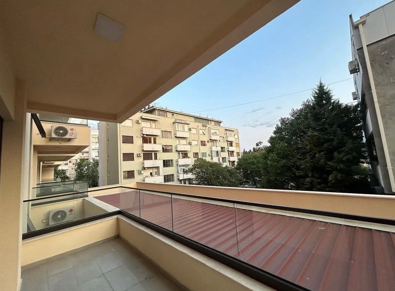 Spacious balcony with a view of surrounding buildings and greenery.