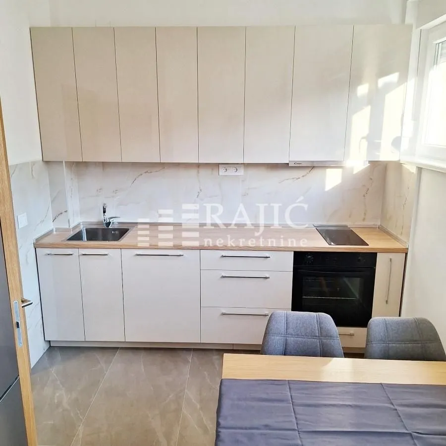 Modern kitchen with white cabinetry and a dining table.