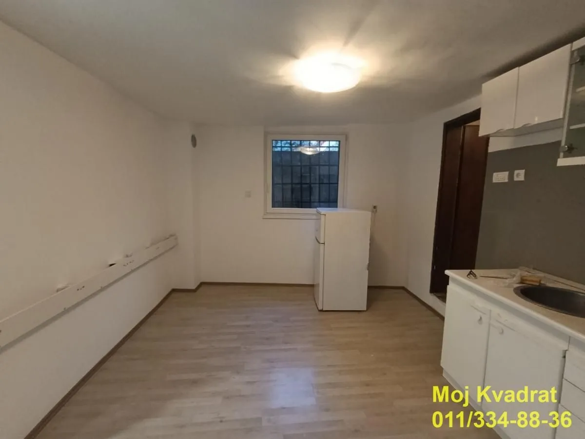 Empty kitchen with a sink, refrigerator and a window.