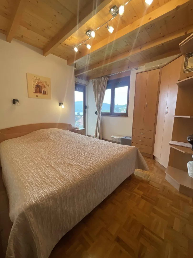 Namještena spavaća soba sa bračnim krevetom i drvenim plafonom.