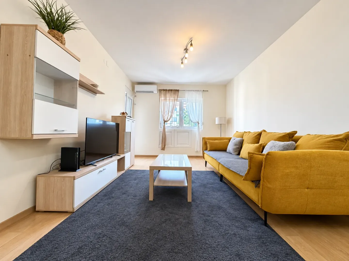 Furnished living room with a yellow sofa, television, and coffee table.