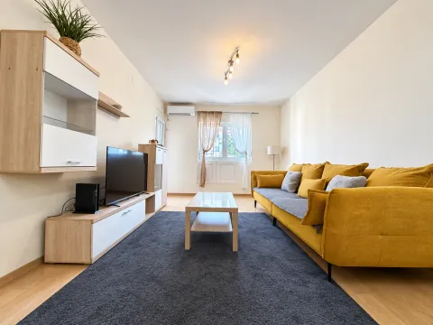 Furnished living room with a yellow sofa, television, and coffee table. - image 2