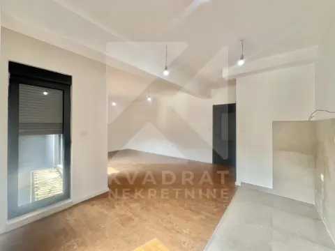 Prazan dnevni boravak sa drvenim podom i izlazom na balkon. - image 4