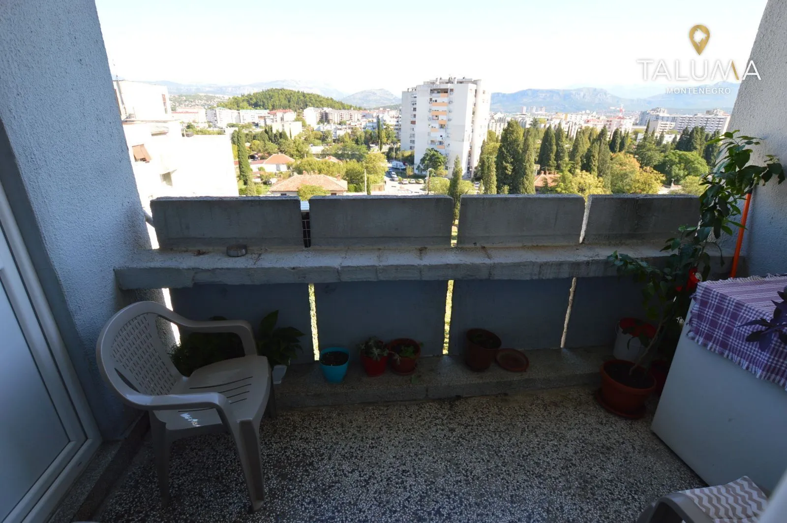 Manji balkon sa pogledom na grad i zelenilo.