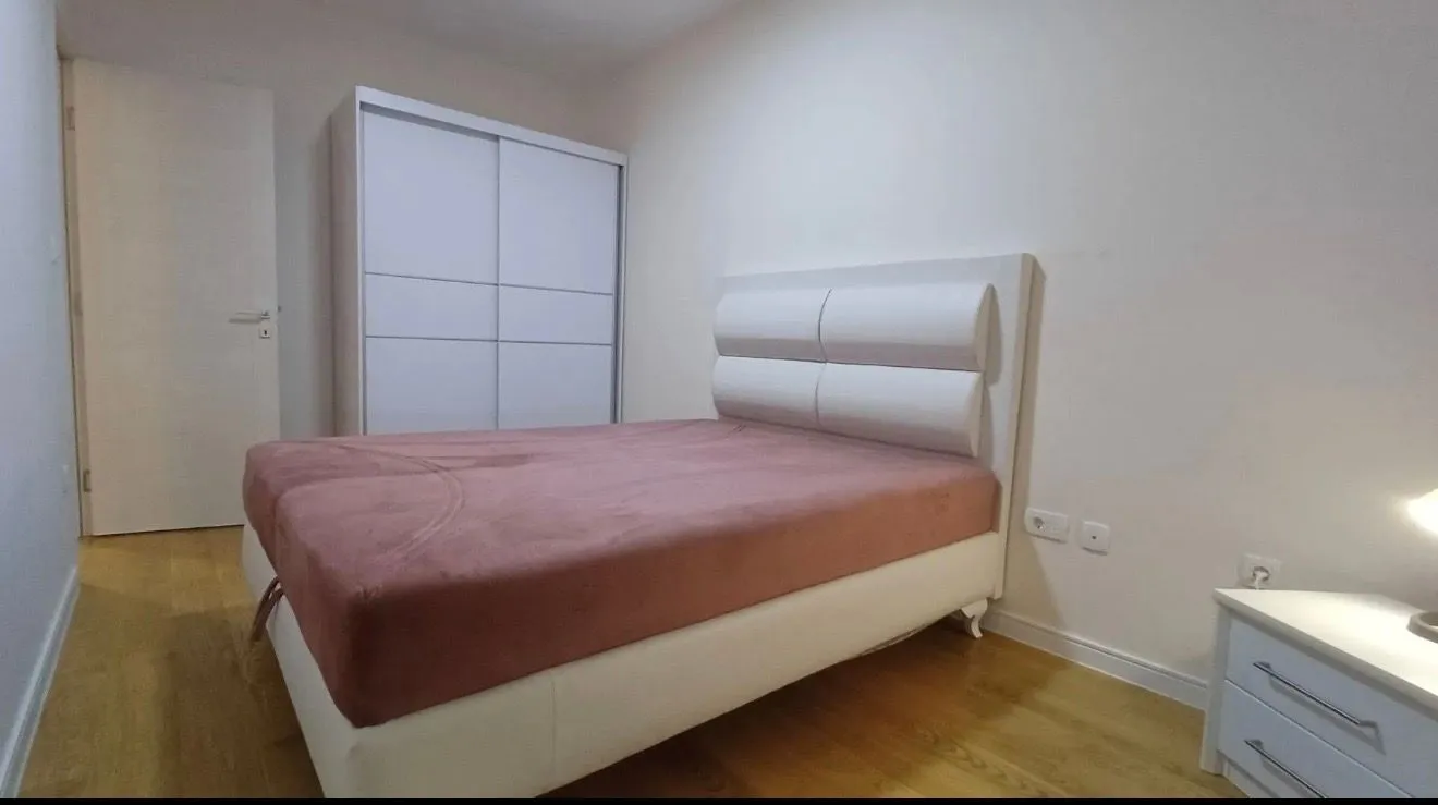 Namještena spavaća soba sa bračnim krevetom i ormarom.