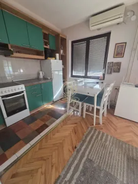 Kuhinja sa zelenim elementima i trpezarijskim stolom. - image 3