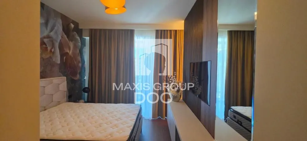 Modern bedroom with a double bed, TV, and curtains.