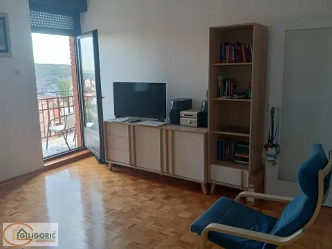 Dnevna soba sa televizorom, policom za knjige i izlazom na terasu. - image 2